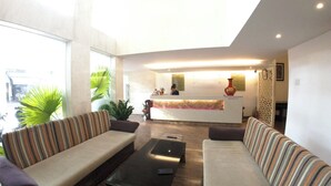 A reception area with a counter, sofas, and potted plants. - Ngoc Linh Luxury Hotel (Ho Chi Minh City)