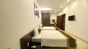 A hotel room with two beds, a desk, a mirror, and a TV.
