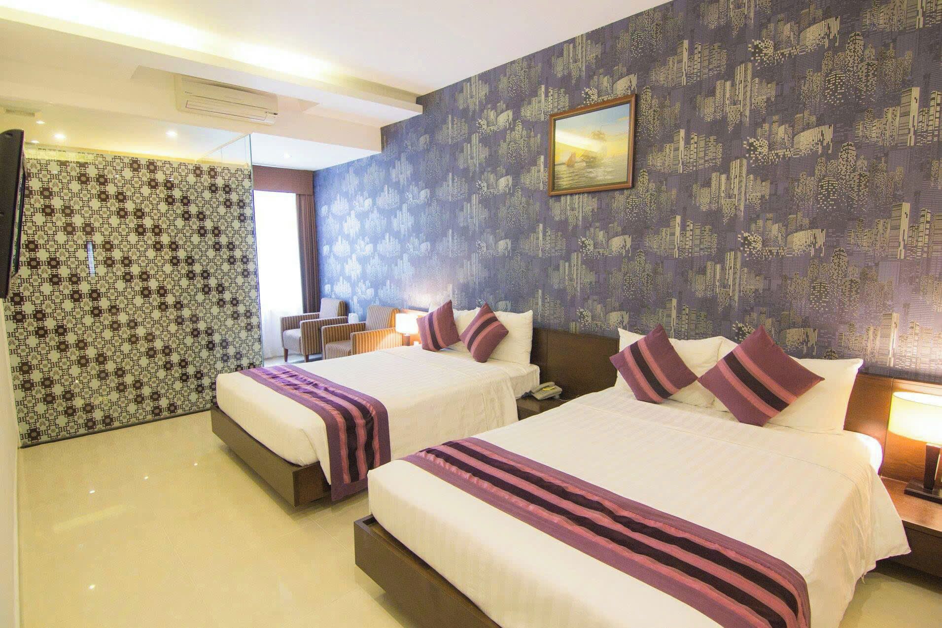 Habitación de hotel con dos camas, papel tapiz estampado, un cuadro en la pared y una ventana con cortinas.