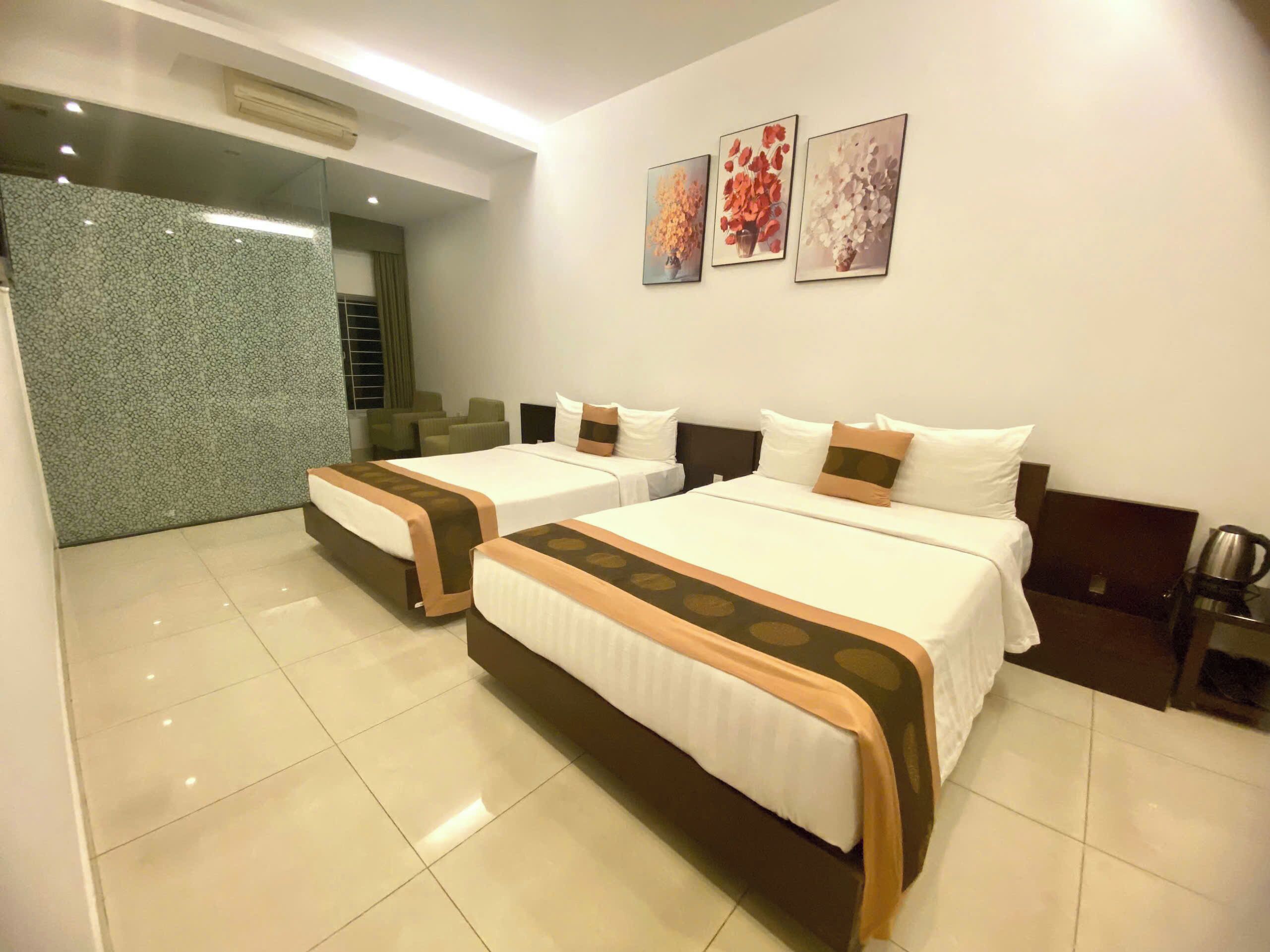 A hotel room with two beds, a coffee machine, and artwork on the wall.