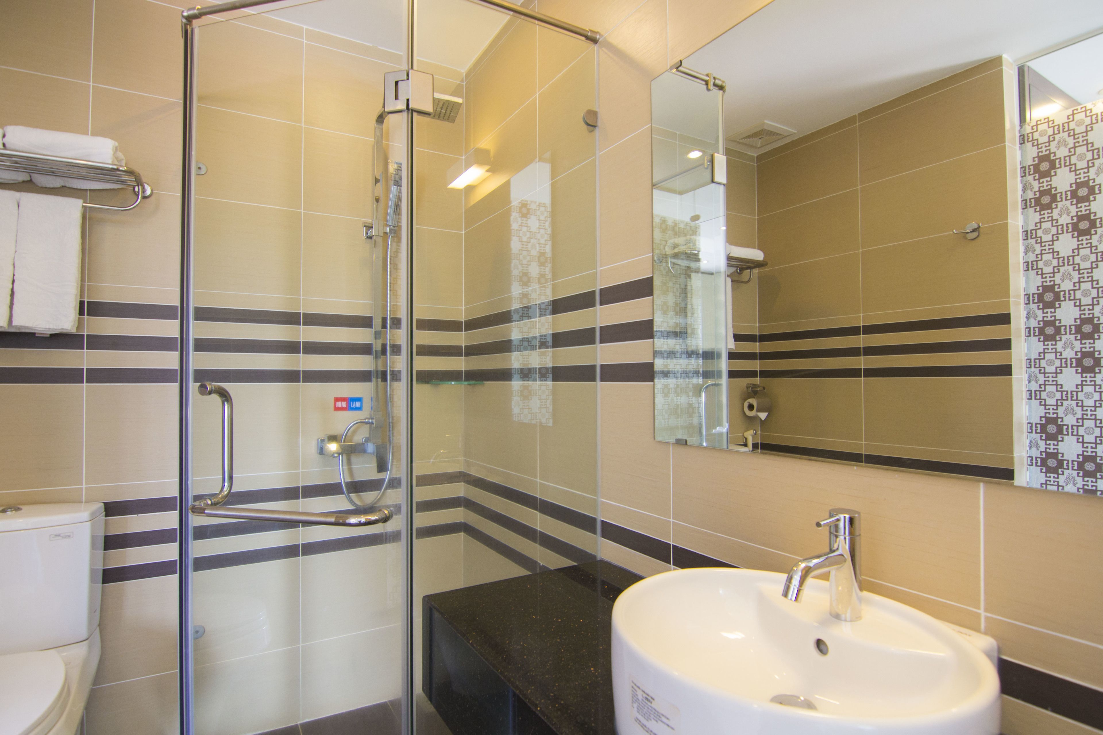 A bathroom with a glass shower enclosure, a sink, and a toilet.