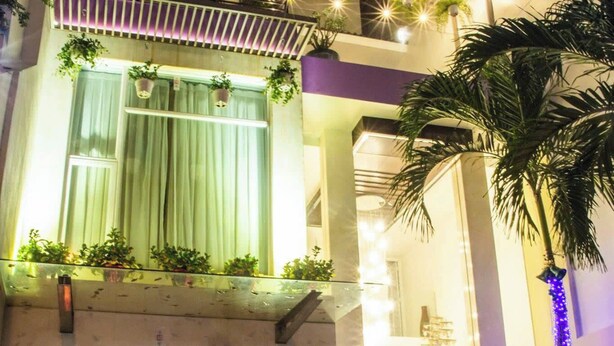 A multi-story building with a glass entrance, potted plants, and a motorcycle parked outside. - Ngoc Linh Luxury Hotel (Ho Chi Minh City)