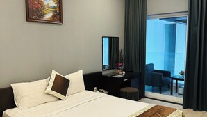 A hotel room with a large bed, a desk, a chair, a window with curtains, and a painting on the wall. - Ngoc Linh Luxury Hotel (Ho Chi Minh City)