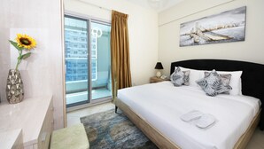 Une chambre d’hôtel avec un lit, une table de chevet, une lampe, un tableau, une fenêtre avec des rideaux et une vue sur les bâtiments environnants.