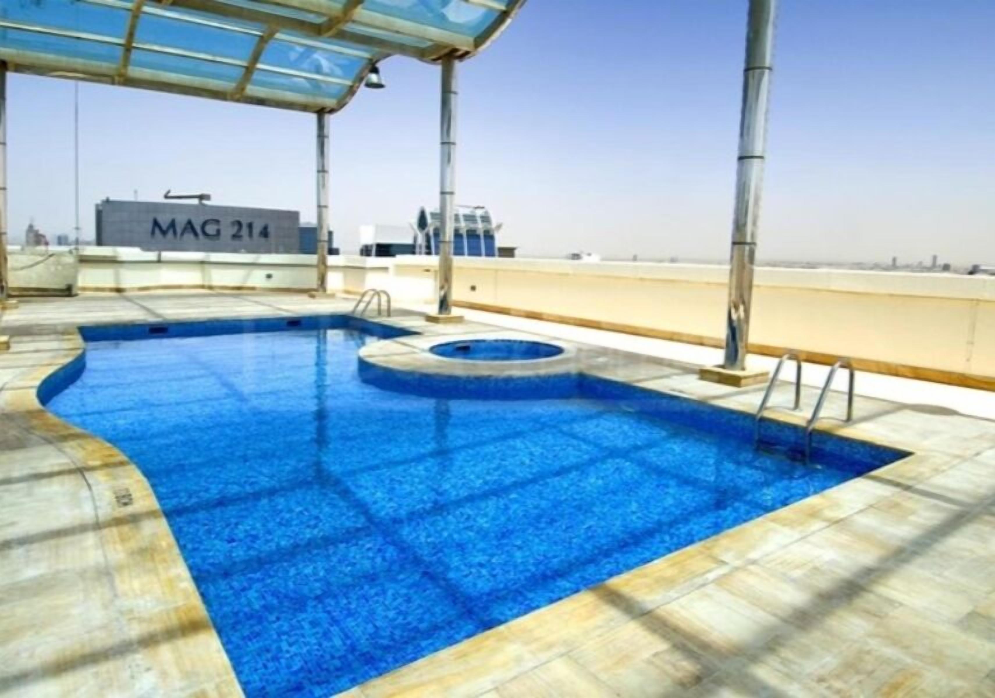 A rooftop pool with a clear view of the city skyline, a covered seating area, and a sign reading "MAG 214".