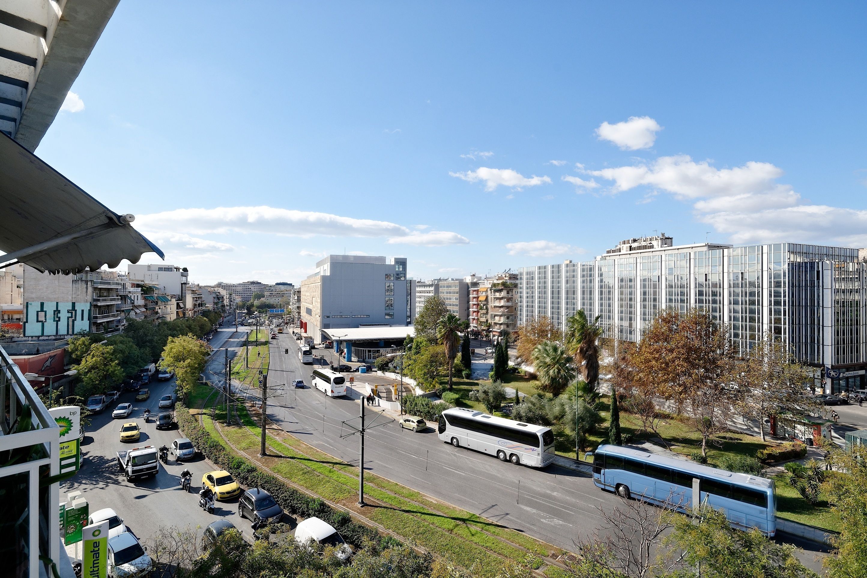 A city street with modern buildings, a bus, and cars.