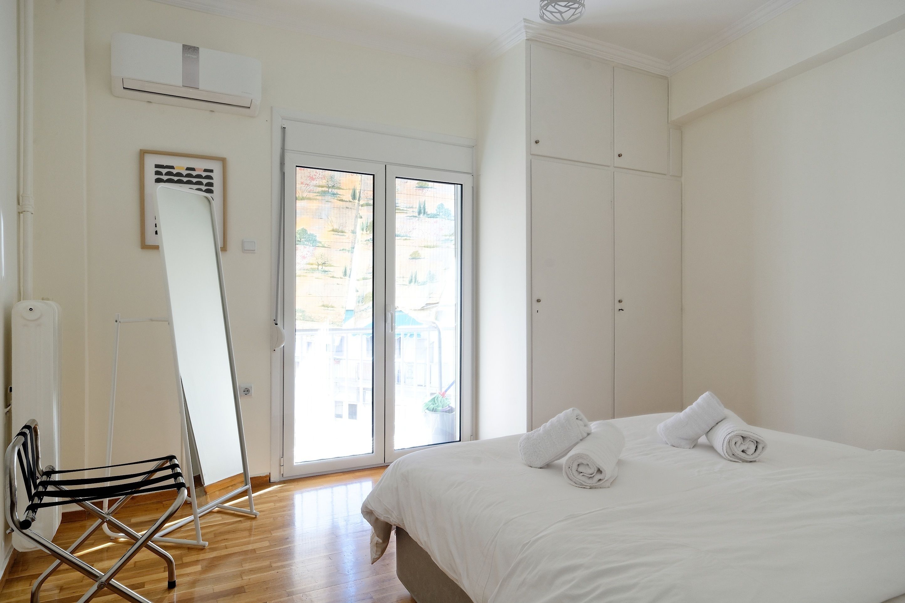 A hotel room with a bed, a whiteboard, a standing fan, and a view through the window.