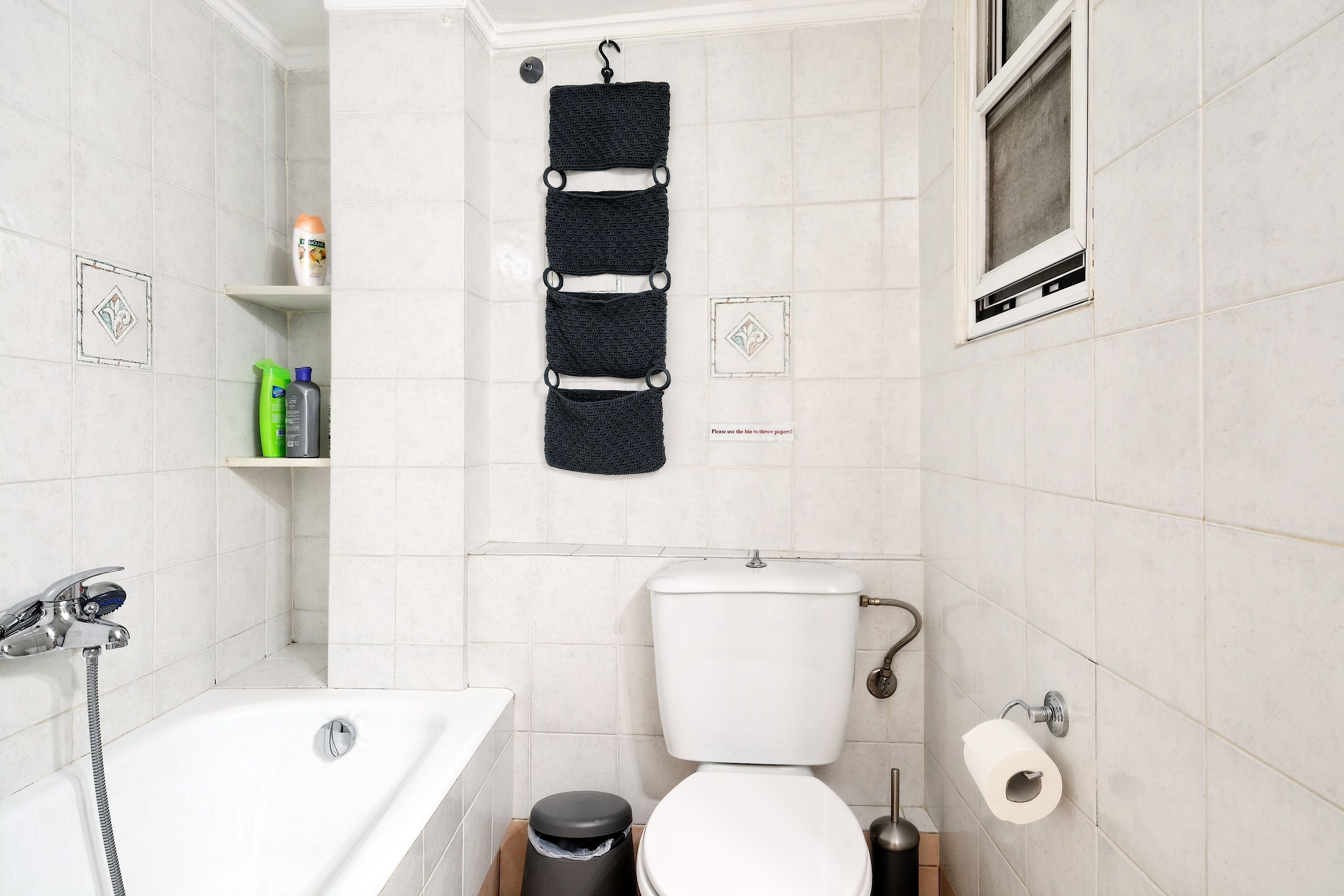 A bathroom with a bathtub, toilet, and a towel rack.