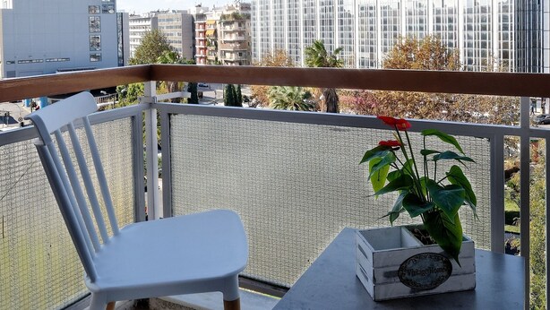 A balcony with a white chair, a small table, and a potted plant. - Athens Heartbeat (Athens)
