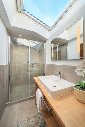 Enjoy a refreshing shower under the skylight, with a glass-enclosed shower and a spacious sink area.