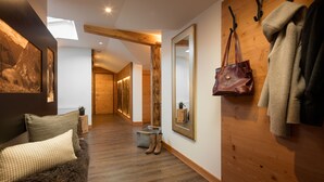 Un couloir doté d’un plancher en bois, d’un banc recouvert de fourrure, d’un miroir et d’un porte-manteau sur lequel est posé un sac à main.