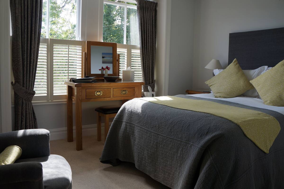 A bedroom with a bed, a desk, and a chair.