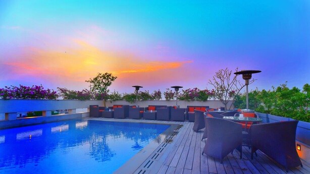 Zona de piscina en la azotea con mobiliario de relax y vistas al atardecer.