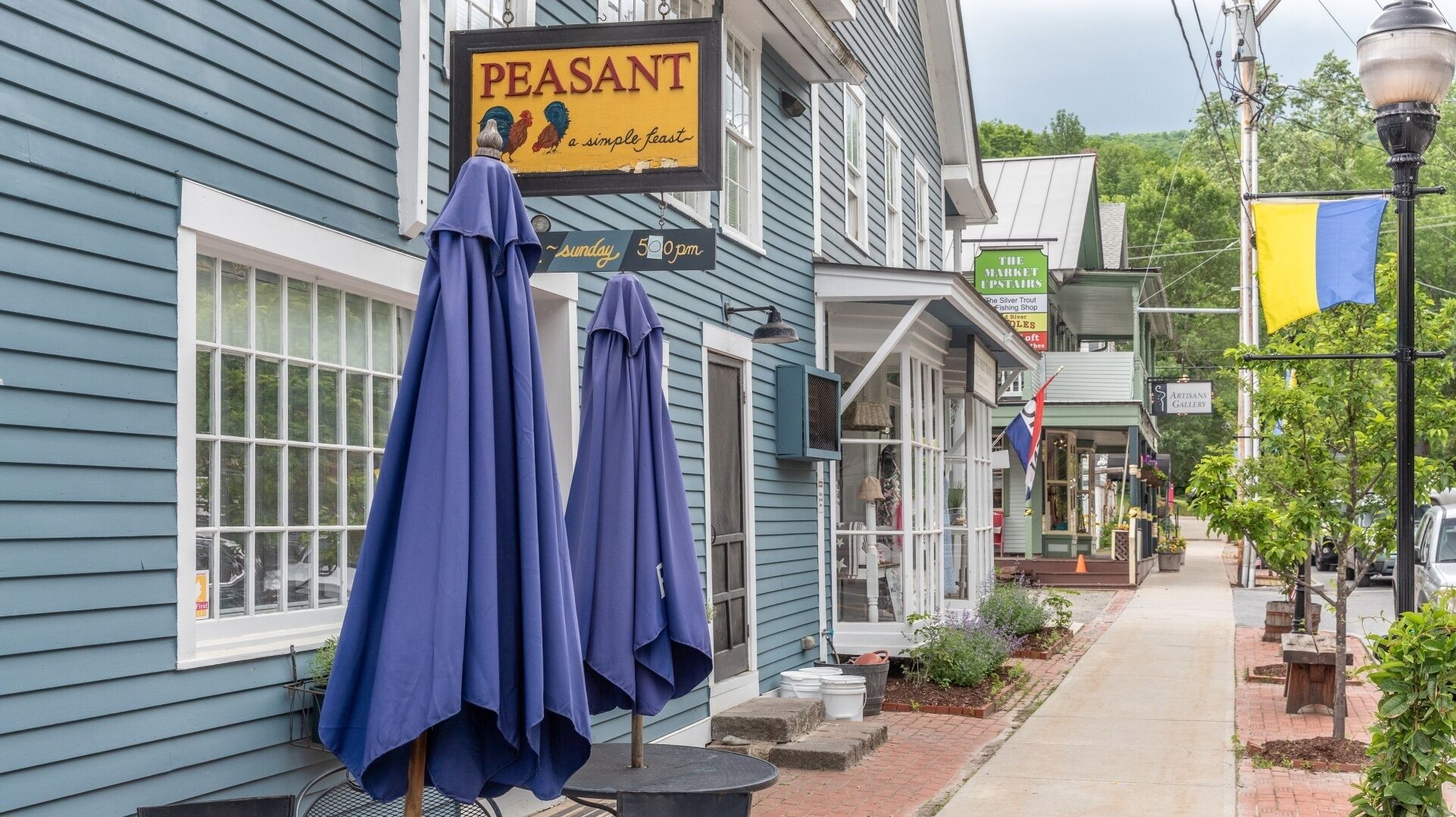 Um edifício com uma placa que diz "PEASANT a simple feast" e outra placa para "THE MARKET UPSTAIRS".