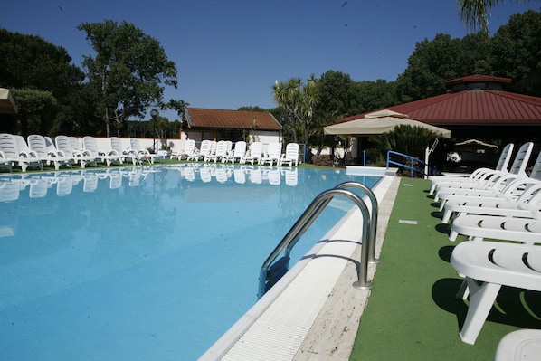 Una piscina con sillones blancos y una zona cubierta.
