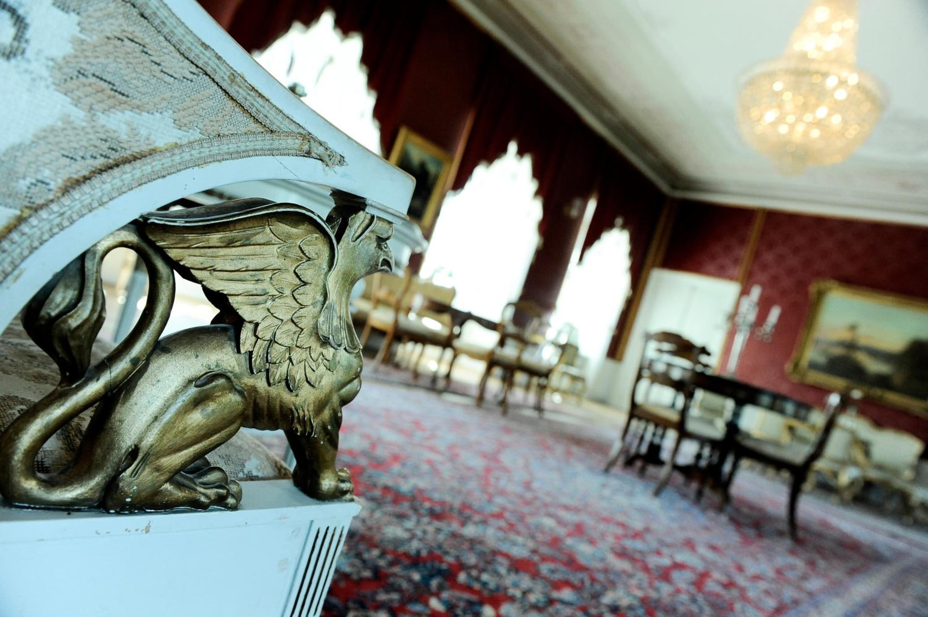 Una habitación con alfombra estampada, candelabro y muebles antiguos.