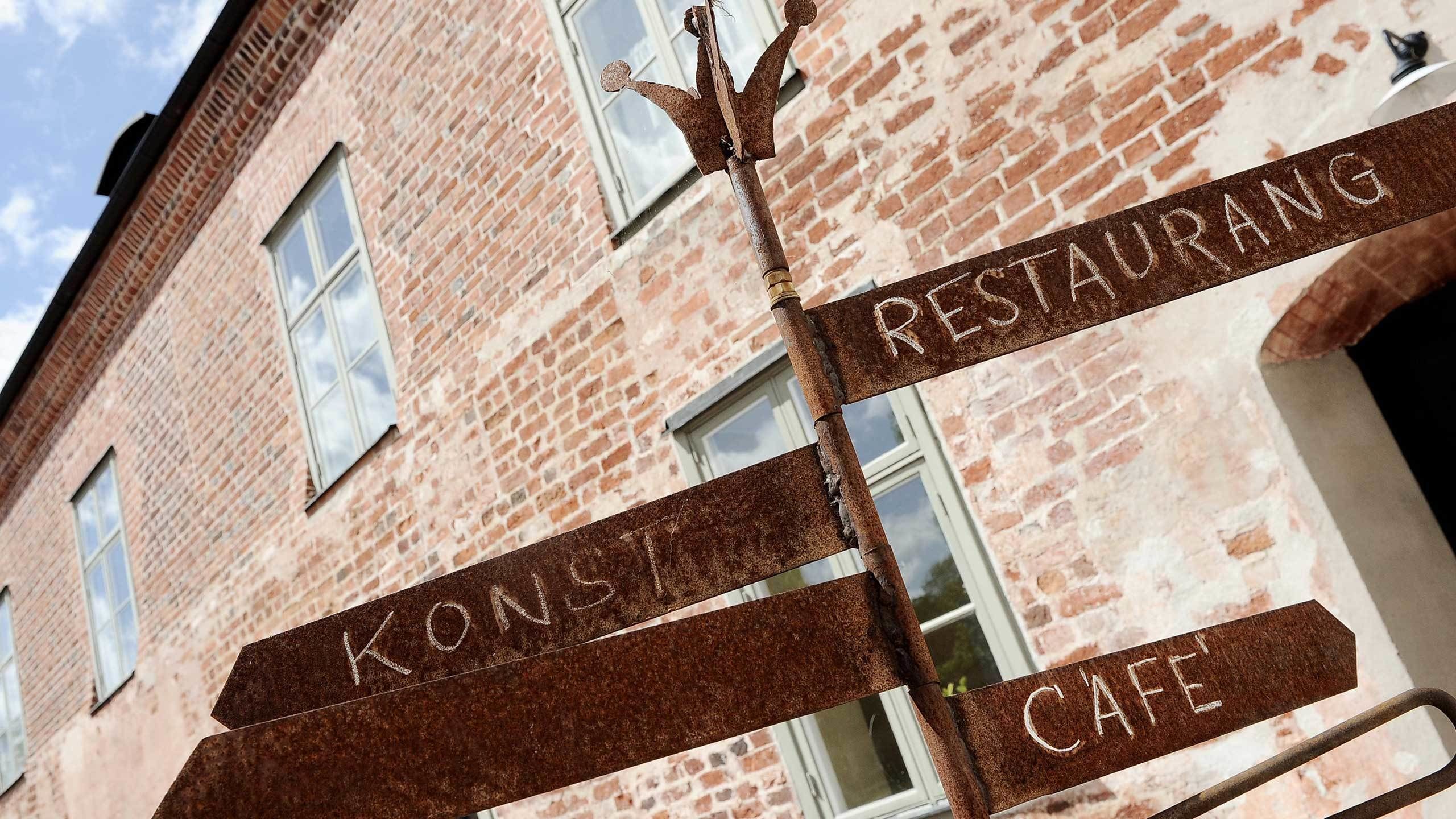 Opastekyltti, jossa lukee ”KONSUM CAFE RESTAURANG”, ja joka osoittaa kahvilan ja ravintolan sijainnin.