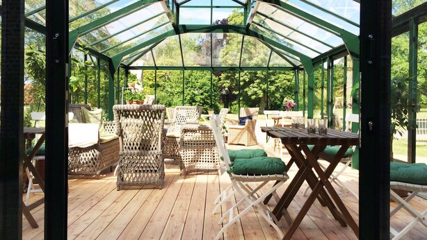 A covered patio area with wicker furniture and a wooden deck. - Bäckaskog Slott (Fjalkinge)