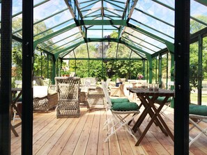 A covered patio area with wicker furniture and a wooden deck. - Bäckaskog Slott (Fjalkinge)