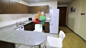Una cocina con encimeras de granito, un refrigerador blanco y armarios de madera.
