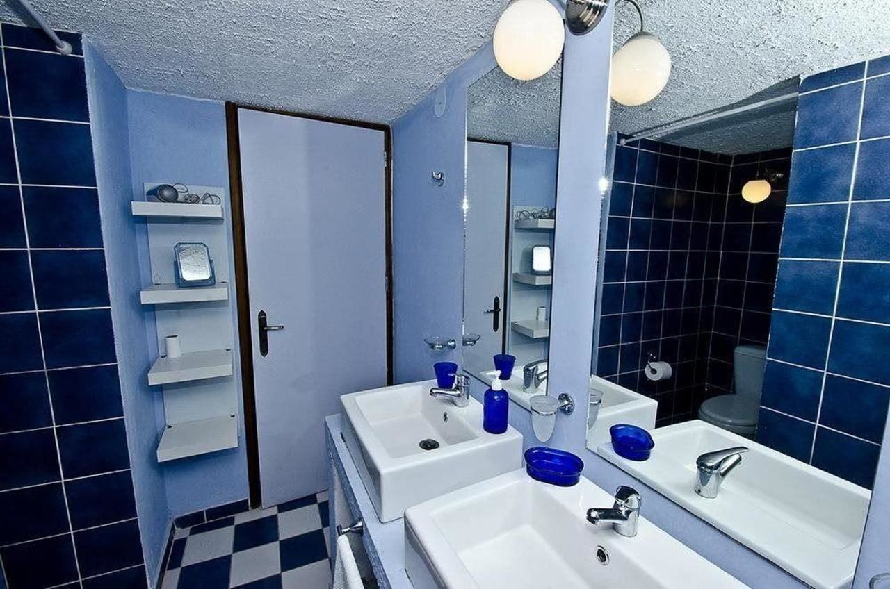 A bathroom with two sinks, a mirror, and a shower. There are shelves with toiletries and a towel rack.