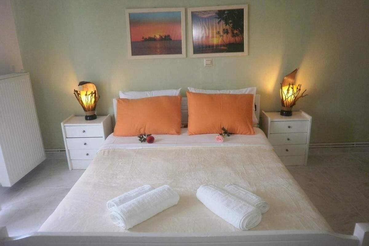 A neatly made bed with two pillows, two bedside tables with lamps, and two framed pictures on the wall.
