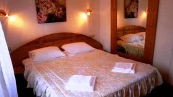 Una cama bien hecha con almohadas y una colcha, un cabecero de madera y dos lámparas de pared.