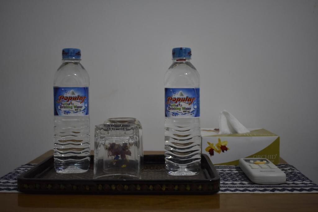 Dos botellas de agua, una caja de pañuelos y un control remoto sobre una bandeja.