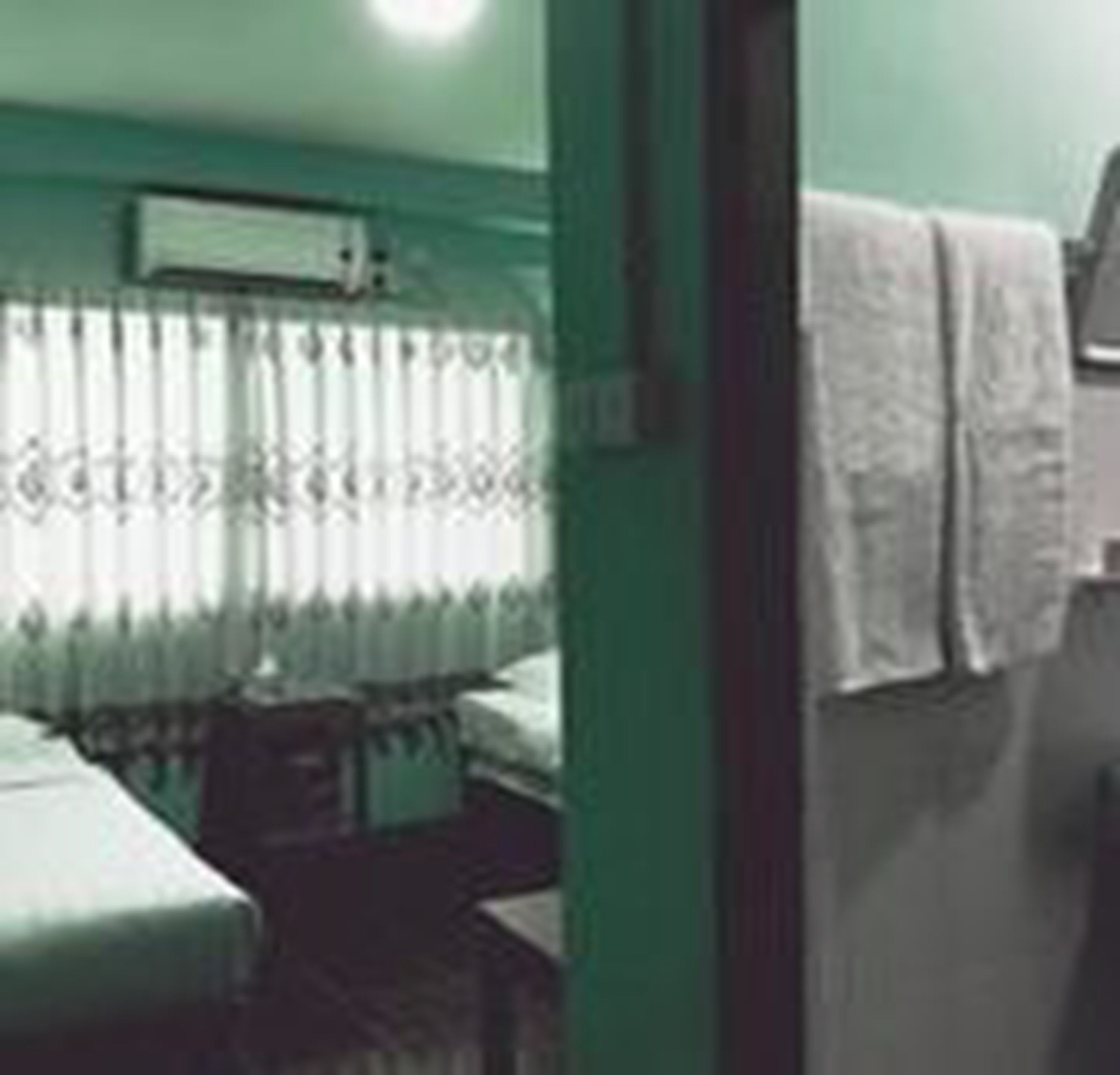 Een kamer met een bed, een tafeltje en een raam met gordijnen.