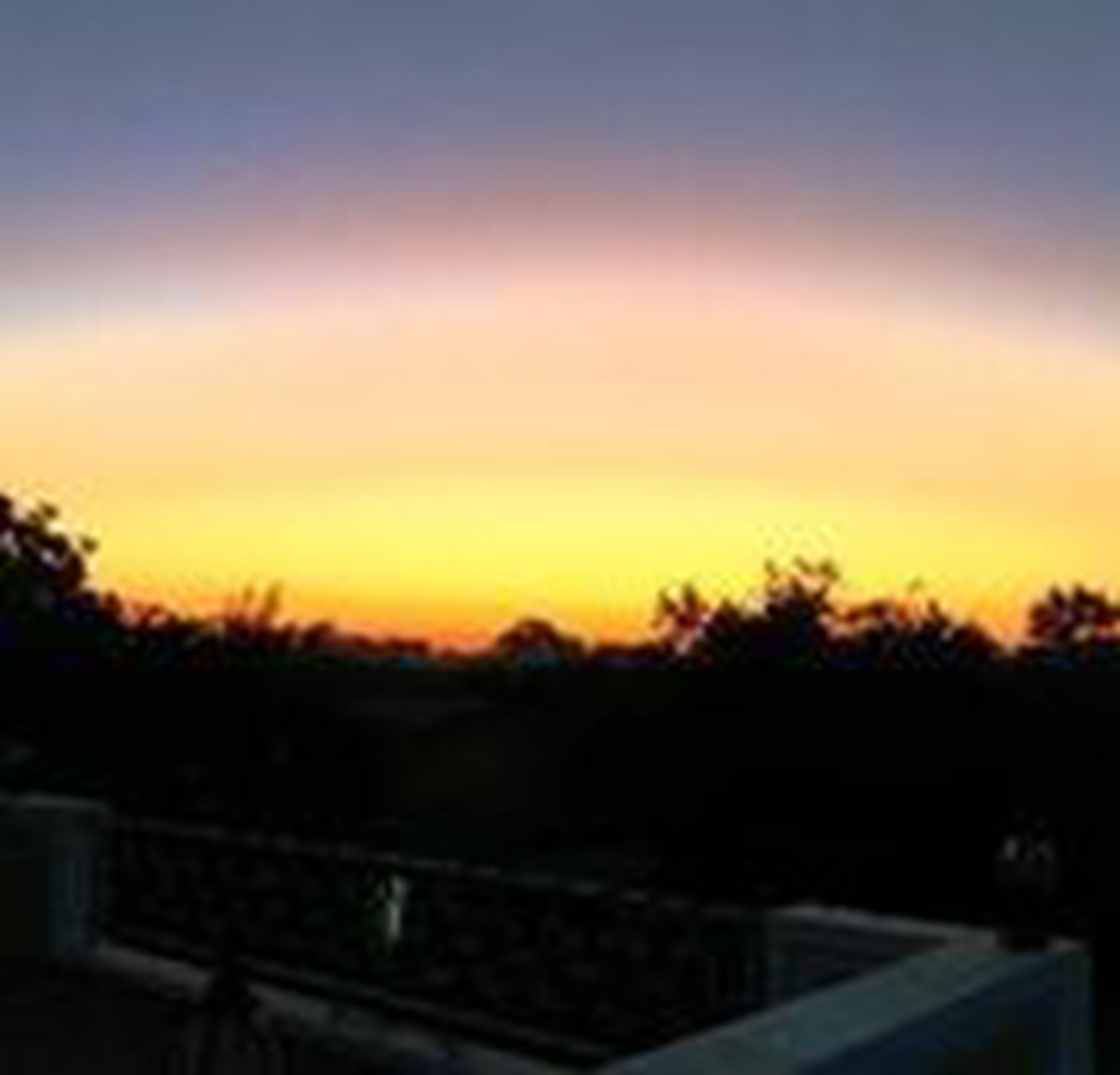 A sunset over a cityscape with buildings silhouetted against the sky.