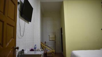 Habitació d'hotel amb un llit, una taula de treball amb un ordinador, una cadira, un televisor fixat a la paret i una escala.