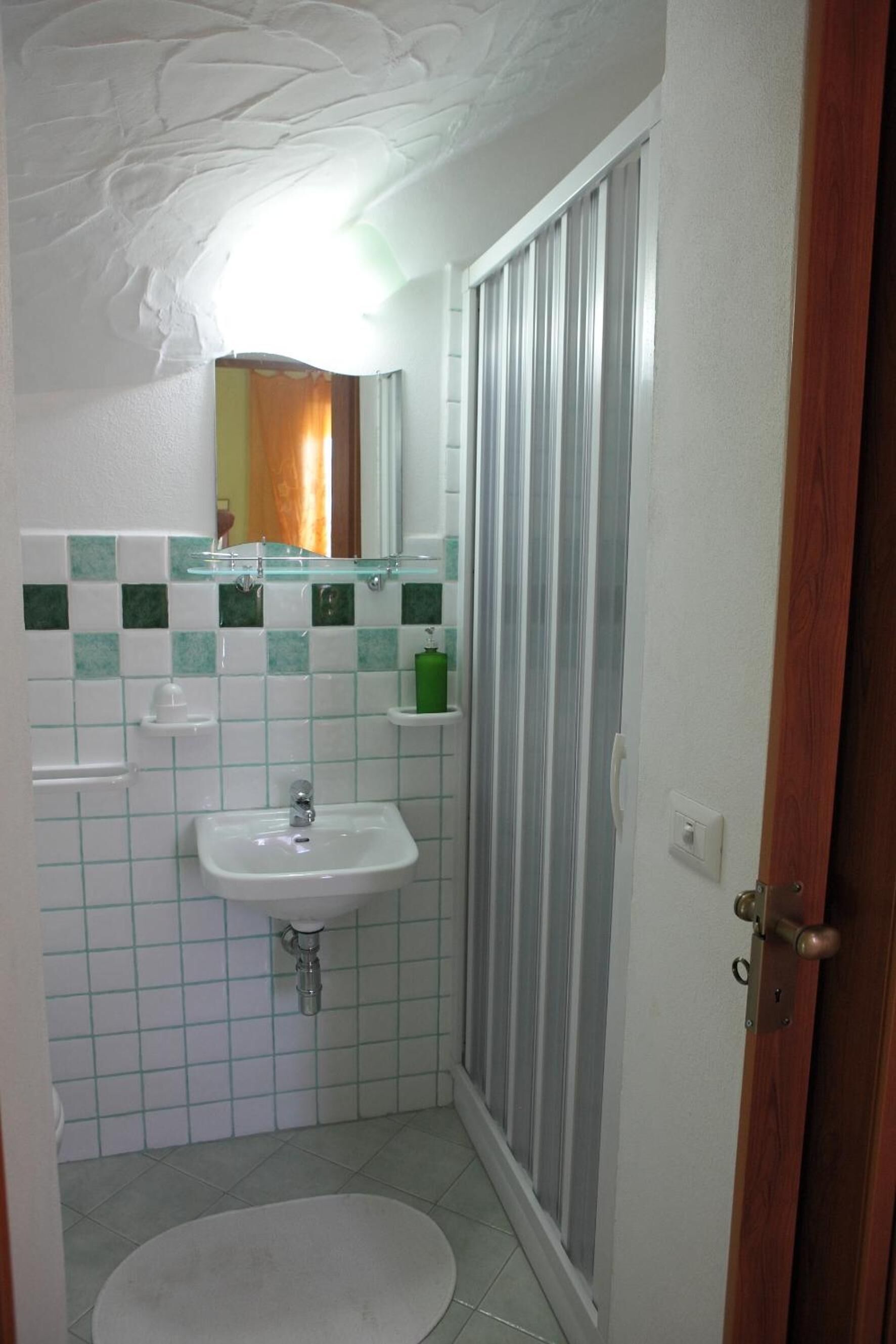 Un baño con lavamanos blanco, espejo y ducha.