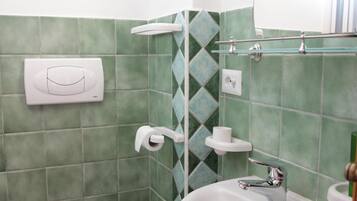 Ein Badezimmer mit Toilette, Waschbecken und grünen Fliesen.