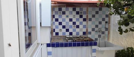 A compact kitchen with a gas stove, a tiled backsplash, and a small sink.