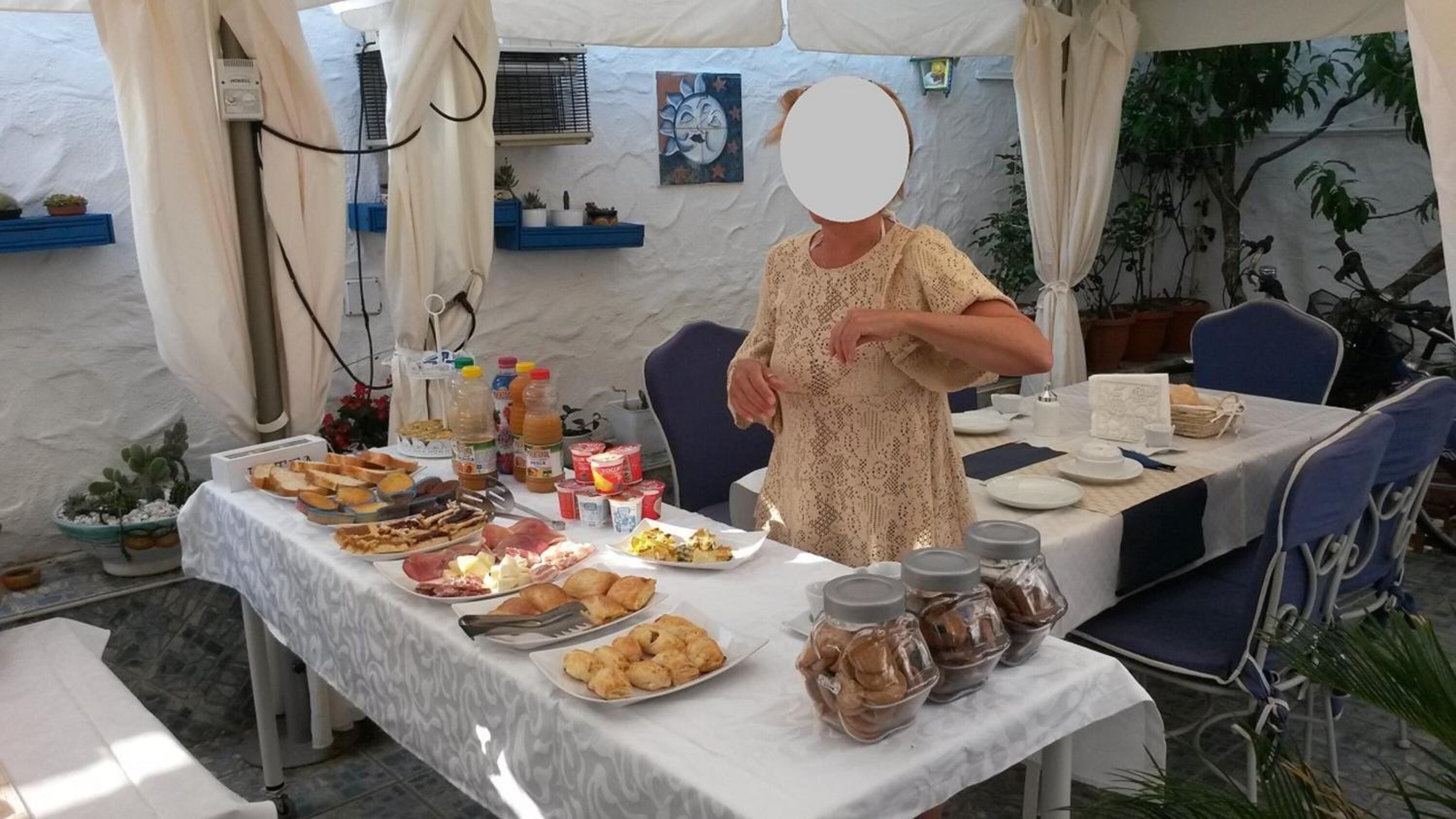 A tented outdoor dining area with a table set for a meal, featuring various dishes and condiments.