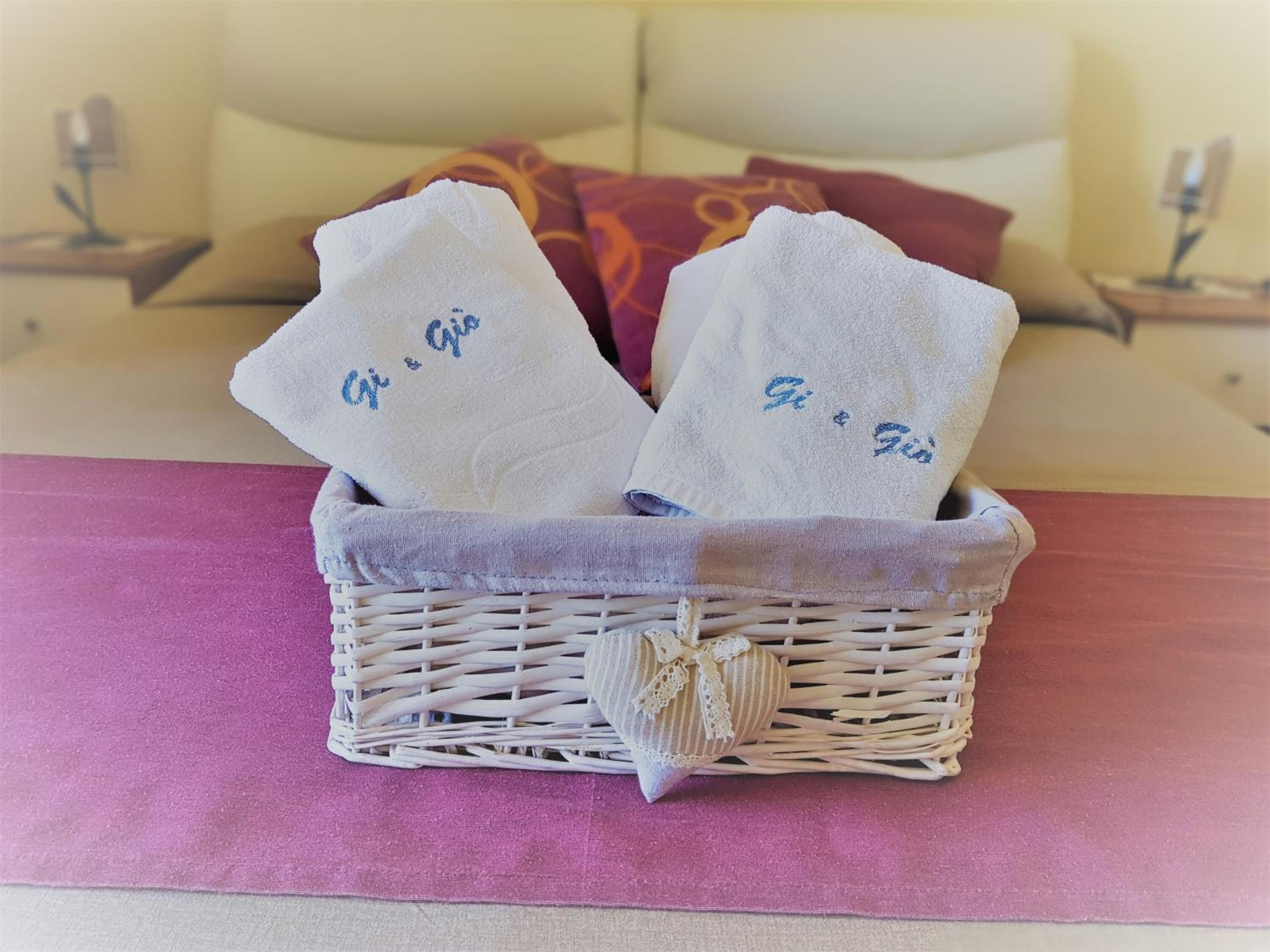 A wicker basket with two towels on a bed.