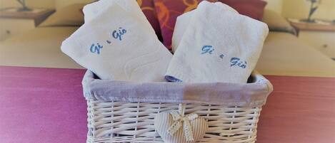 A wicker basket with two towels on a bed.