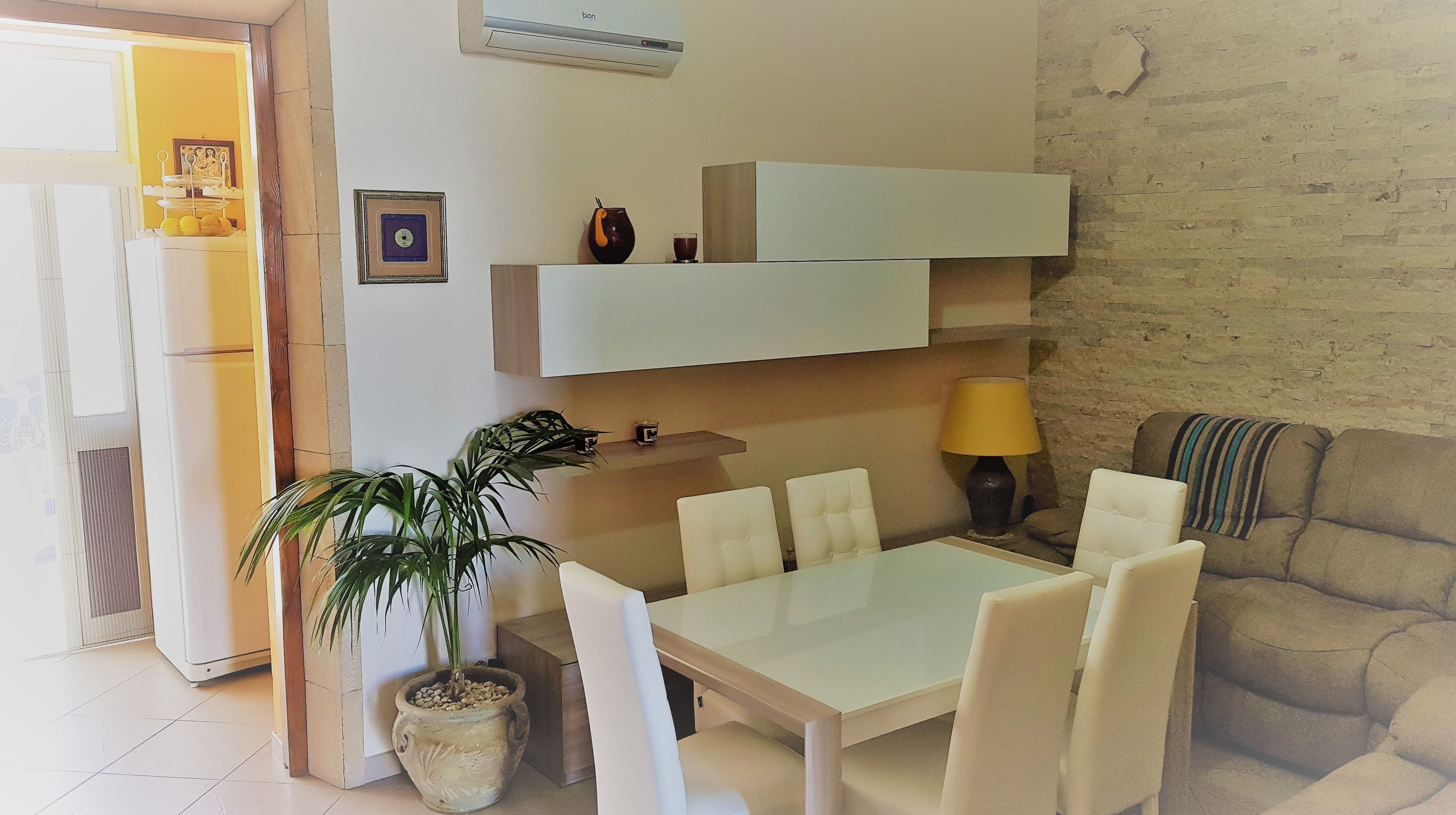 Un salon moderne comprenant une table à manger, des chaises, un canapé, une plante en pot et une lampe.