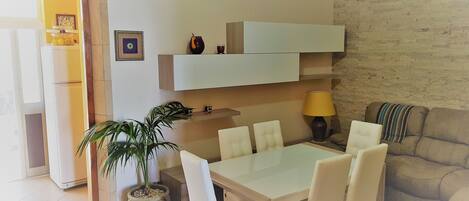 Un salon moderne comprenant une table à manger, des chaises, un canapé, une plante en pot et une lampe.