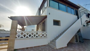A modern two-story house with a covered outdoor area, a staircase, and a visible door. - Residence Giglio Torre Pali (Salve)