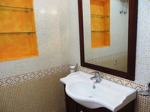 A bathroom with a white sink, a mirror, and tiled walls.