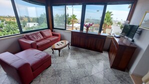 A living room with a red sofa, a small coffee table, and a TV on a wooden cabinet. - Residence Giglio Torre Pali (Salve)