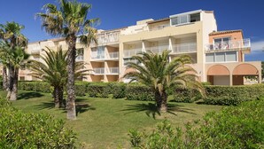 A multi-story hotel with balconies, palm trees, and a well-maintained lawn. - Vacancéole - Palmyra Golf (Agde)