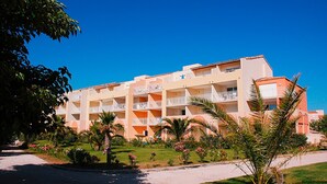 A multi-story hotel with balconies, surrounded by palm trees and a well-maintained lawn. - Vacancéole - Palmyra Golf (Agde)