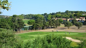 A golf course with a clear view of the green, sand bunkers, and surrounding trees. - Vacancéole - Palmyra Golf (Agde)
