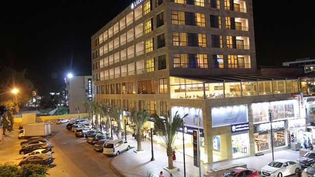 A multi-story hotel with a modern design, featuring a prominent sign at the top. - Lacosta Hotel (Aqaba)