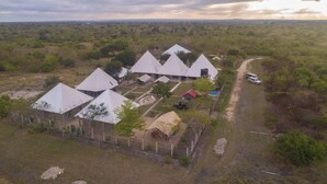 A series of pyramid-shaped buildings with a central courtyard, surrounded by a fence, set in a rural landscape.