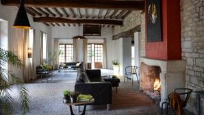 A spacious living area with a fireplace, comfortable seating, and a large window providing natural light. - Domaine de l'Ocrerie (Pourrain)