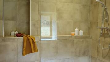 Un espace douche moderne doté d’une porte en verre, d’une barre d’appui et d’un pommeau de douche.