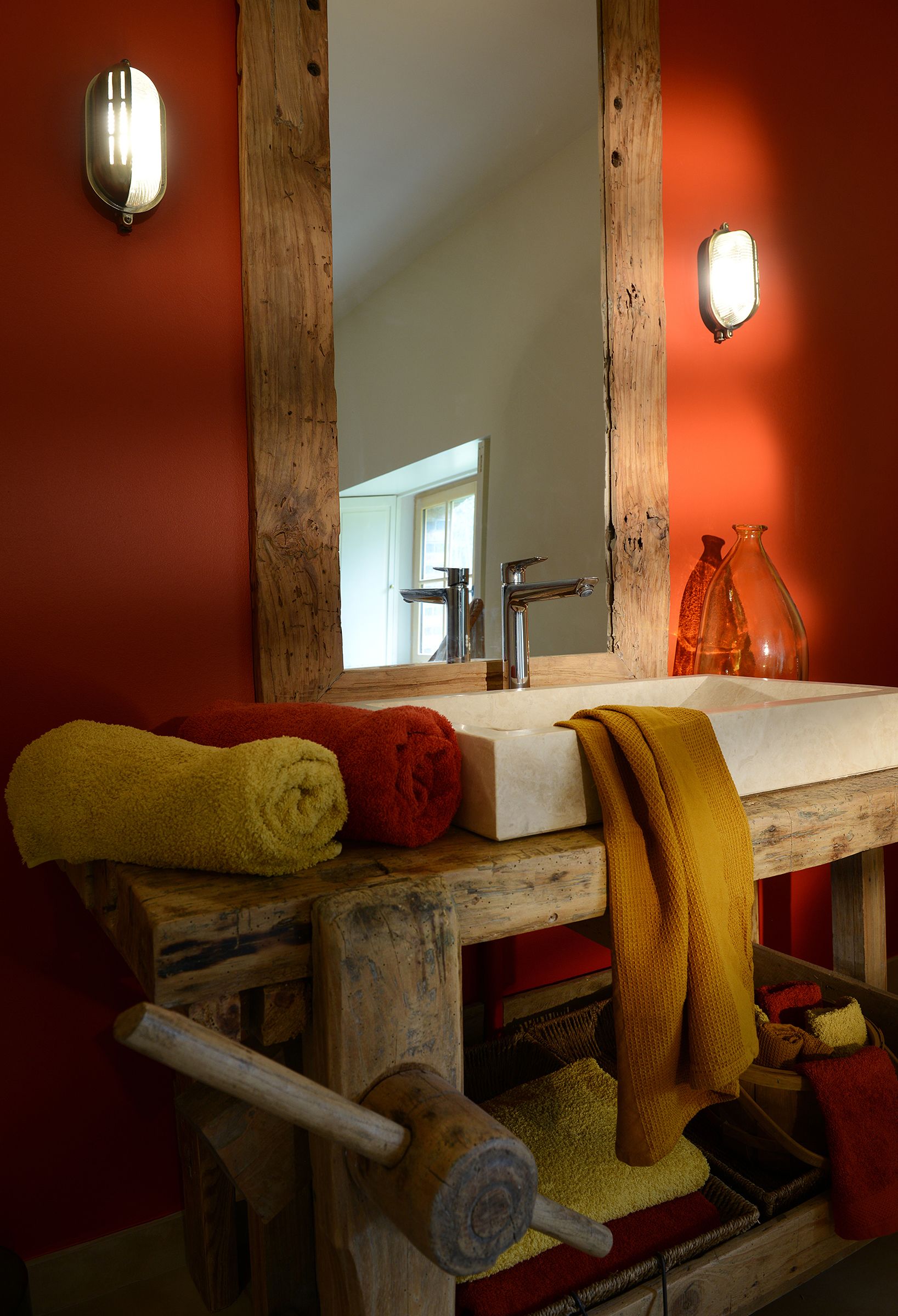 Un baño rústico con un lavabo de madera, un espejo y toallas.